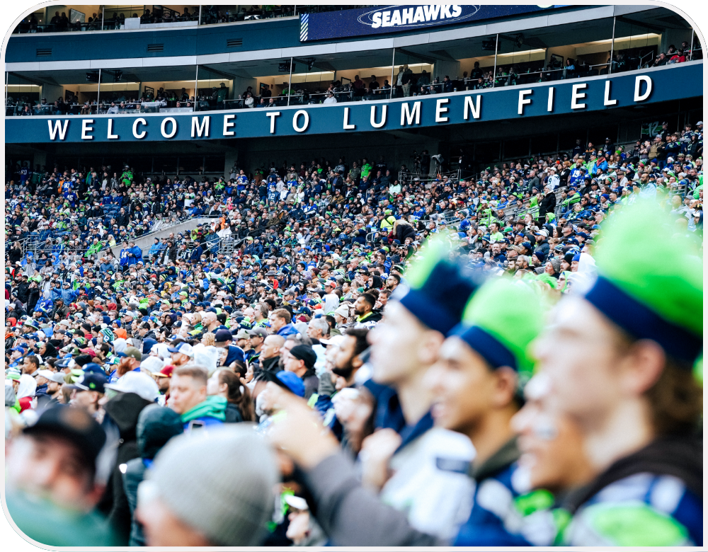 Lumen Field stadium full of fans dressed in green and dark blue under a sign reading “Welcome to Lumen Field.”