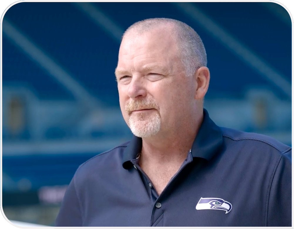 Sterling Monroe wearing a navy Seahawks polo and standing in the empty stadium.