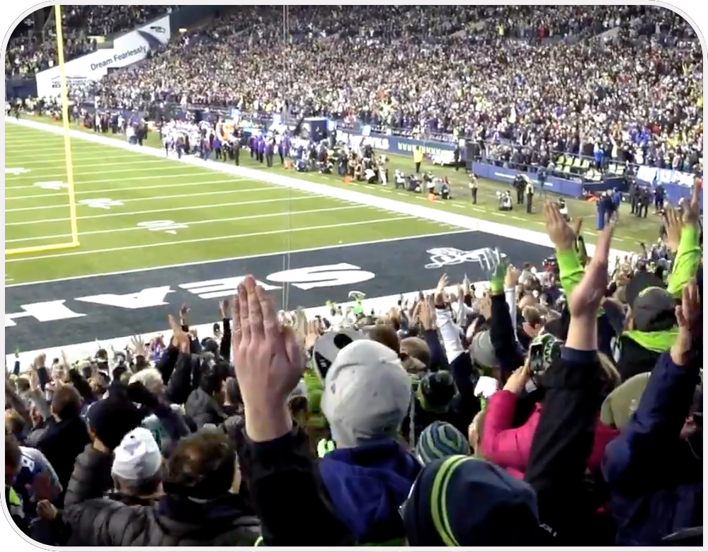 Lumen Field stadium filled with Seahawks fans cheering and the Seahawks on the sidelines.