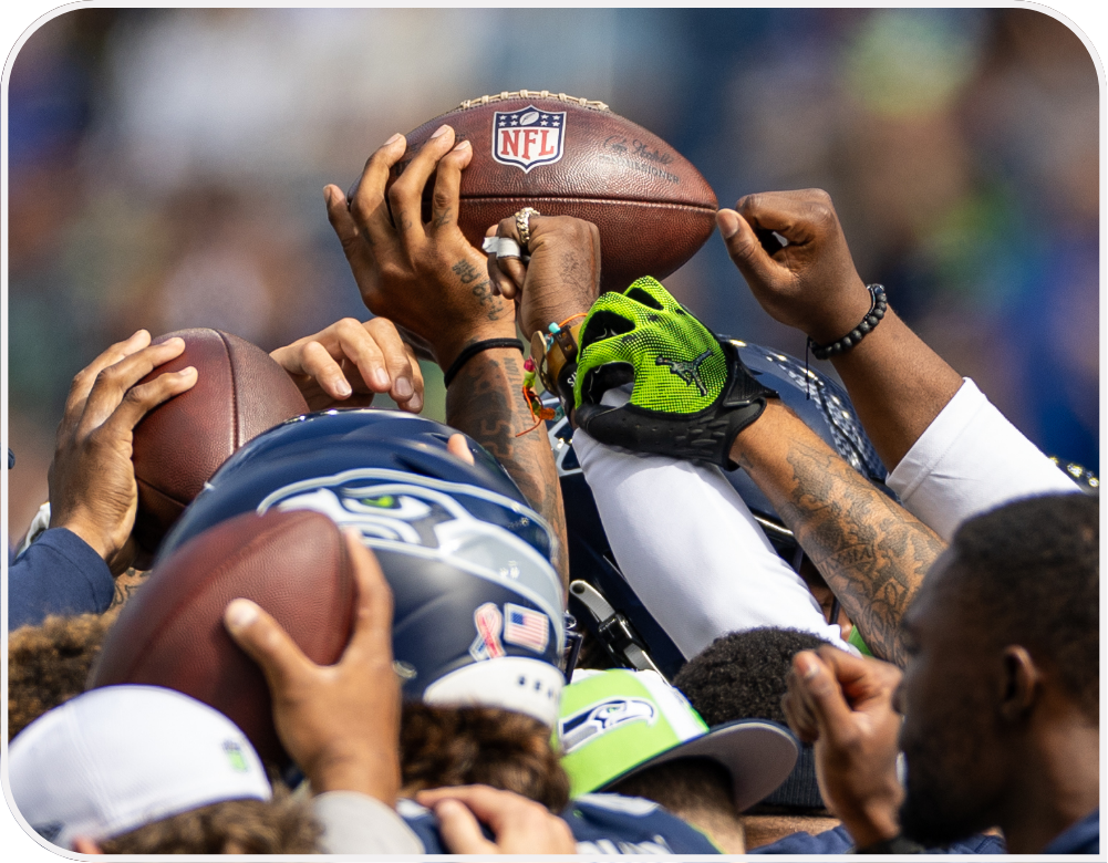 Several Seahawks players gathered holding up footballs.