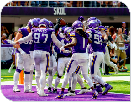 The Vikings wear purple uniforms and huddle on the field. 
