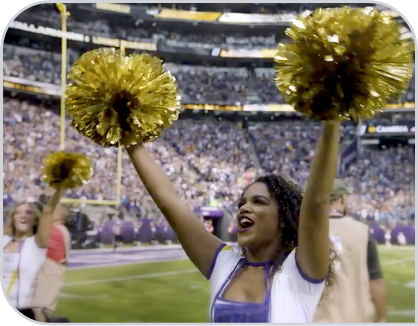 Cheerleader uses pom poms at a game. 