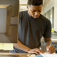 Man researching and writing notes at desk