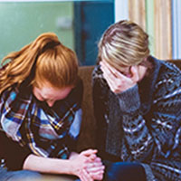Two people crying and comforting each other