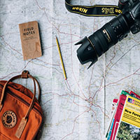 Map with a backpack, notebook, camera, pencil, and pad