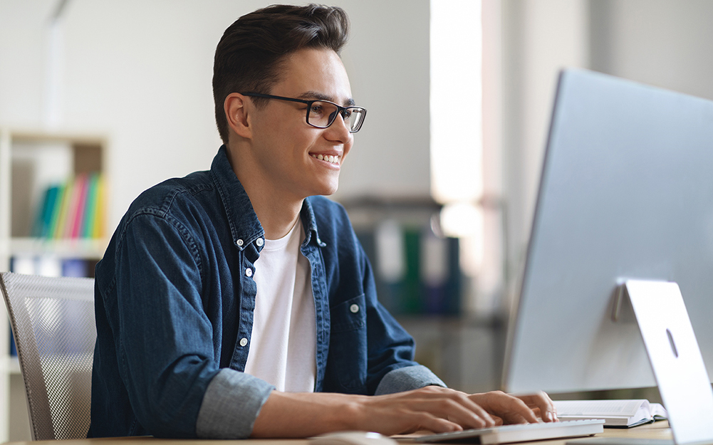 Male student looking at computer screen and smiling