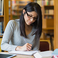 Woman writing notes in library