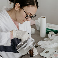 Scientist pouring liquid into a small glass bottle
